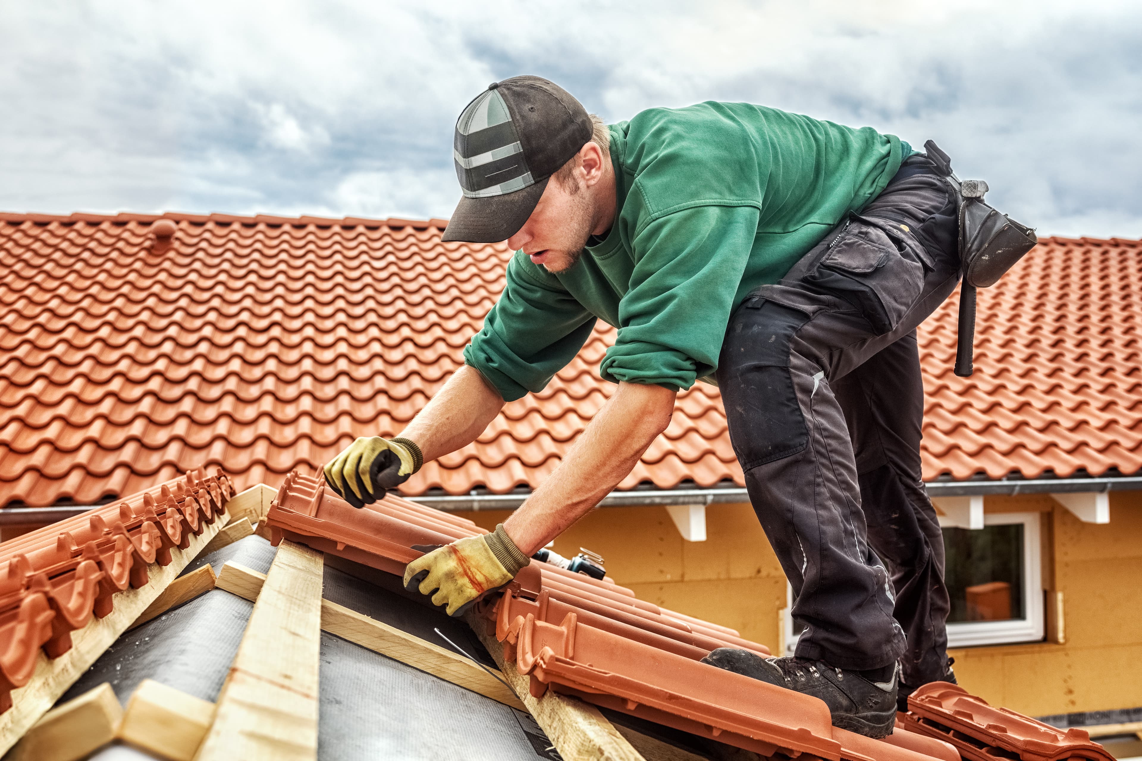 Roofer installing clay tile on a specialty roofing project